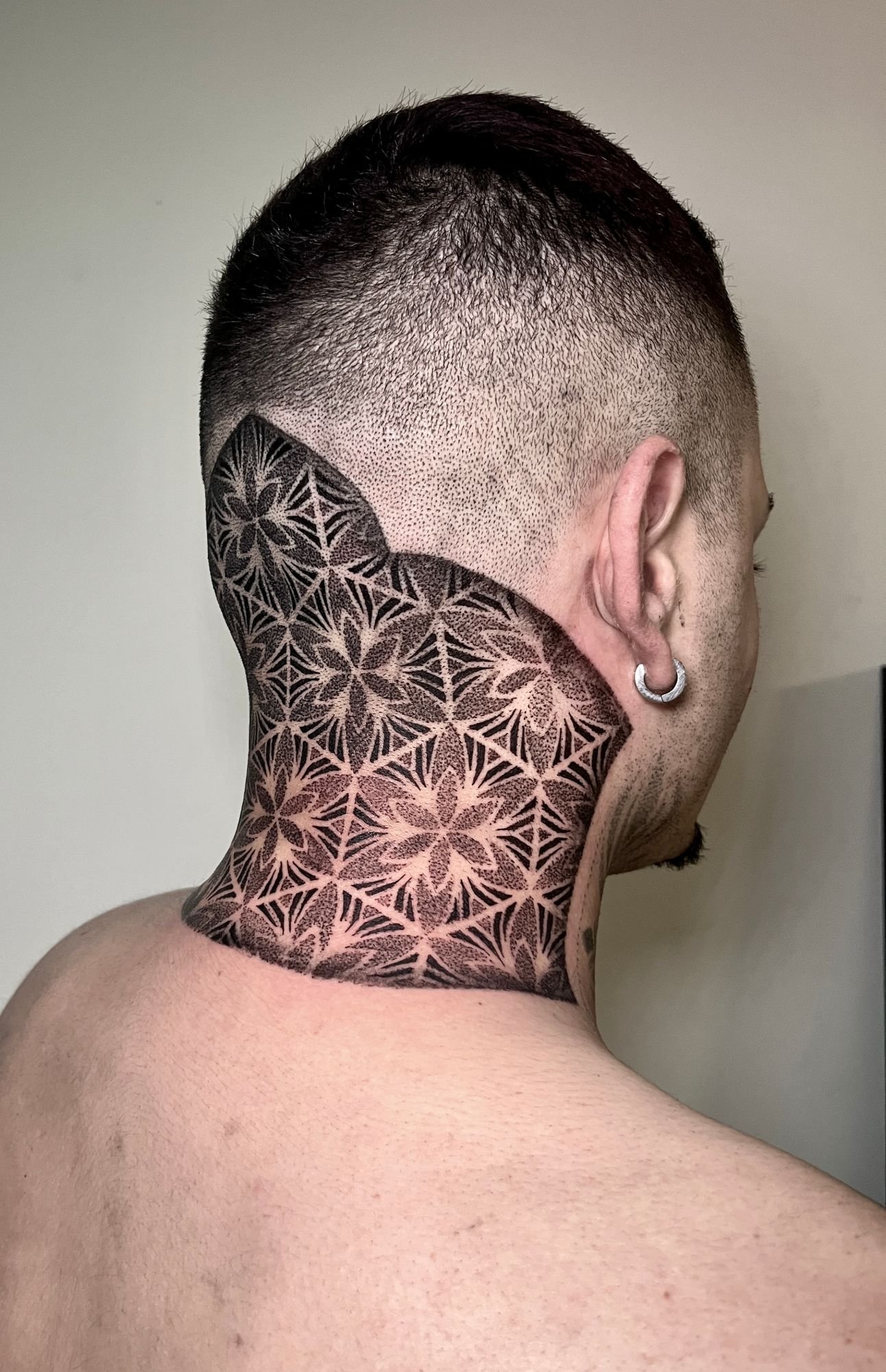 Patrón de geometría sagrada en dotwork tatuado en la nuca